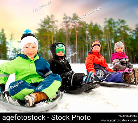 happy little kids sliding on sleds in winter