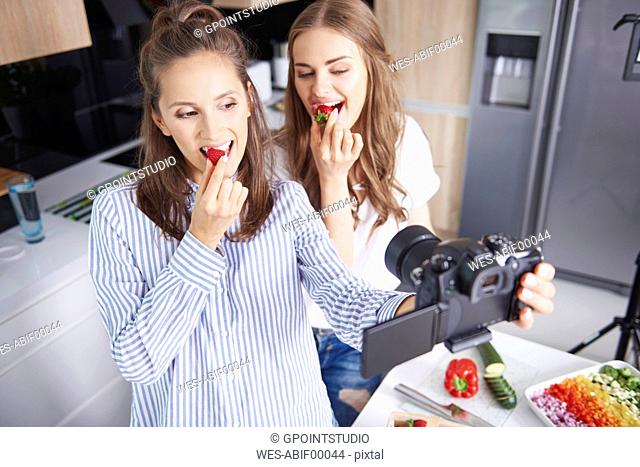 Food bloggers filming theirselves eating strawberries