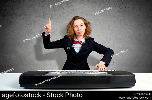 Funny crazy woman in suit and bow tie playing piano and pointing with finger up