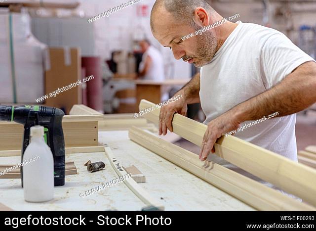 Carpenter applying glue on wood while working at workshop