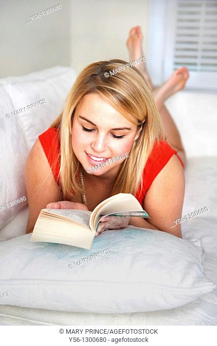 Young blonde woman reading on couch