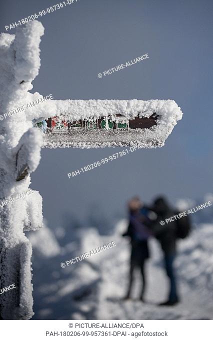 Hikers standing at an iced up sign at the Teufelsstieg pointing towards the Brocken in Germany, 06 Febuary 2018. Several centimetres of snow are lying there