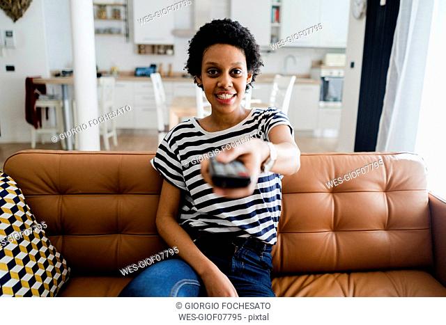 Portrait of smiling young woman watching Tv at home