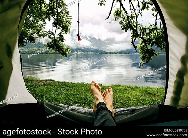 Feet on man laying in camping tent at lake