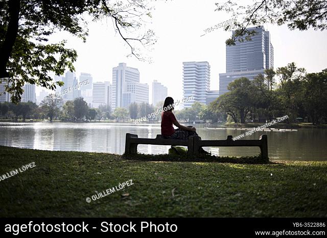 A young woman rests in a bench of the Lumpini Park in Bangkok, Thailand