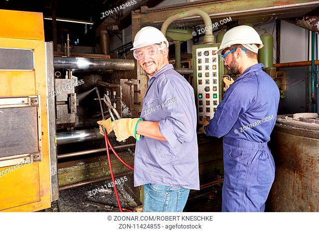 Arbeiter bedienen ein Steuerpult für die Fertigung in einer Schmiede oder Metallfabrik