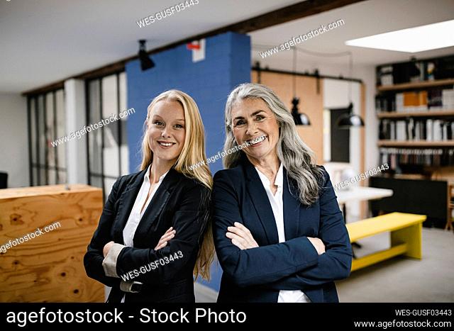 Portrait of happy mature and young businesswoman in loft office