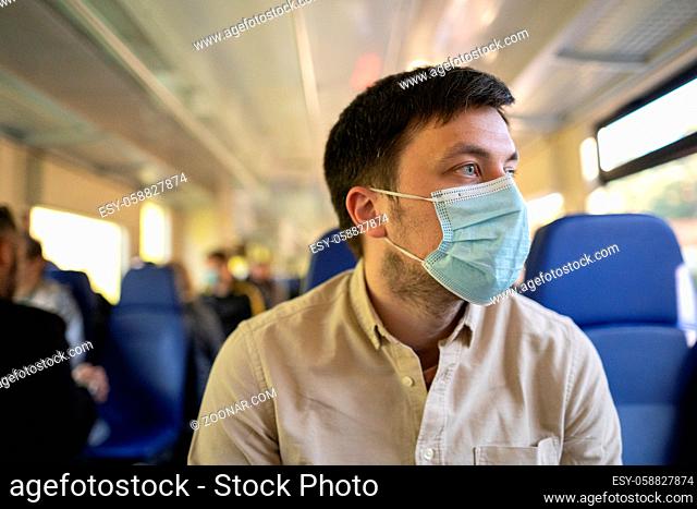 Male passenger wearing face mask during covid-19 lockdown inside train. New normal lifestyle concept. Social distancing when traveling by public transport