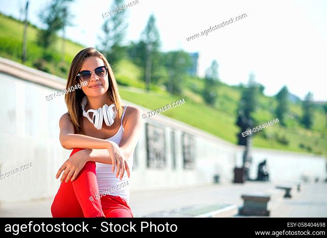 Attractive brunette girl in summer park wearing headphones