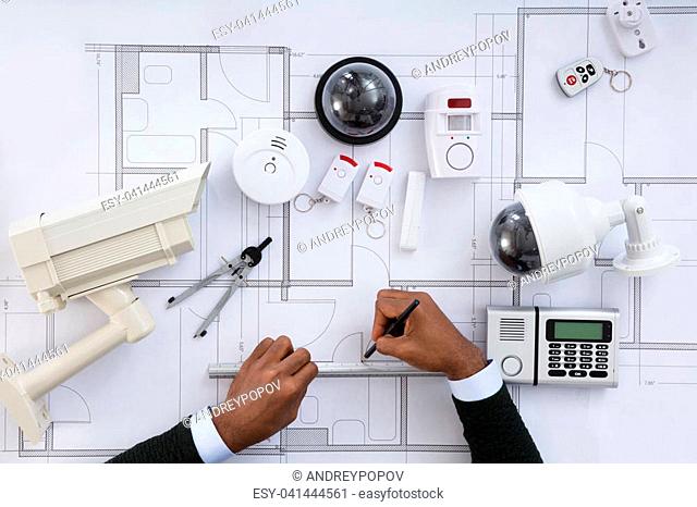 High Angle View Of Person Hands Working On Blueprint With Security Equipments