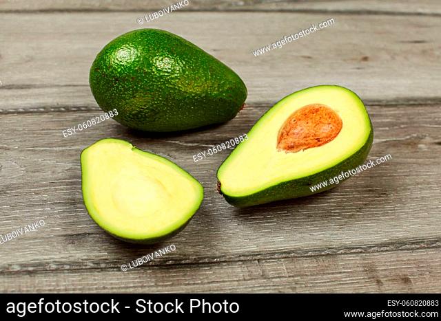 Avocado cut in half with whole pear in back, on gray wood table