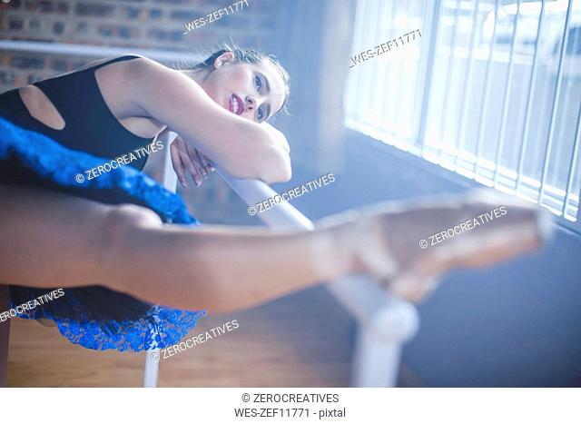 Ballet dancer stretching leg at studio