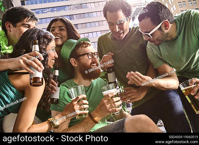 Group of friends hanging out on balcony of bar enjoying the St Patrick's Day festivities drinking beer
