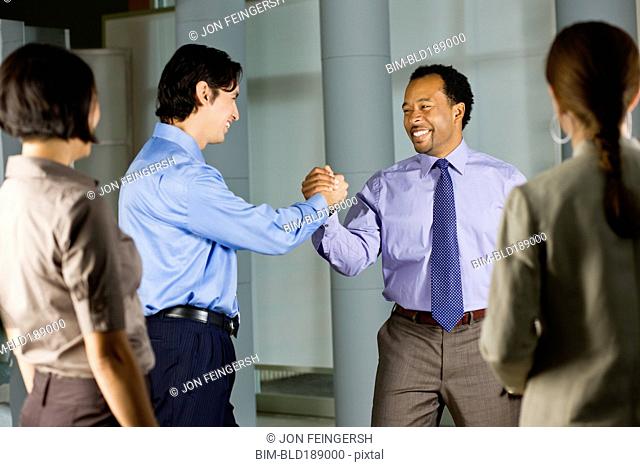 Multi-ethnic co-workers shaking hands in office