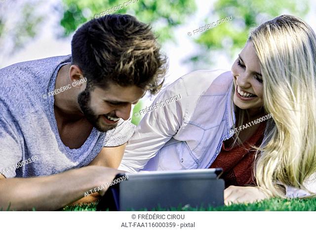 Couple using digital tablet in park