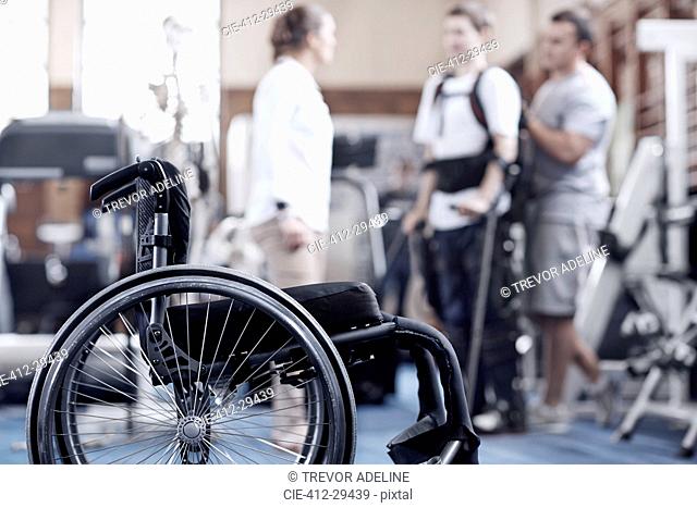 Man receiving physical therapy with wheelchair in foreground