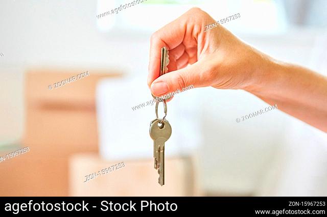 Hand von Makler oder Eigentümer hält Schlüssel zum neuen Haus nach dem Einzug