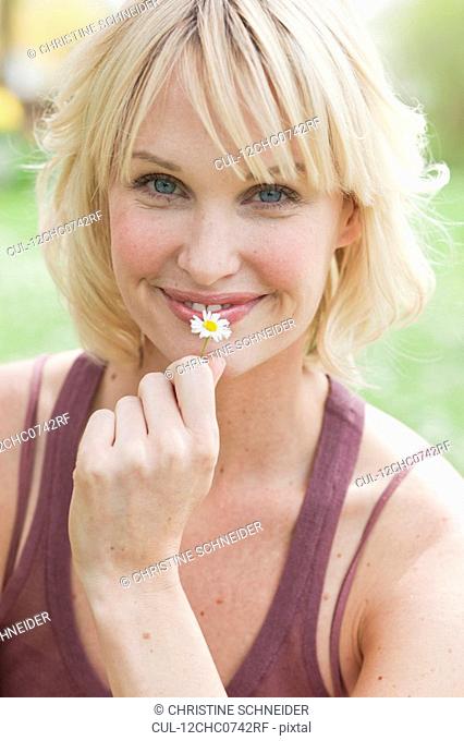 woman with flower smiling at viewer