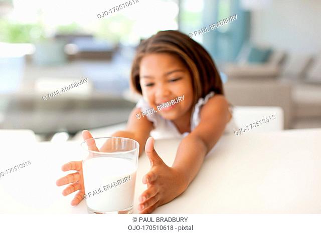 Girl reaching for glass of milk
