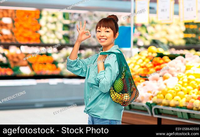 happy asian woman with food in reusable string bag