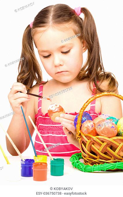Little girl is painting eggs preparing for Easter, isolated over white