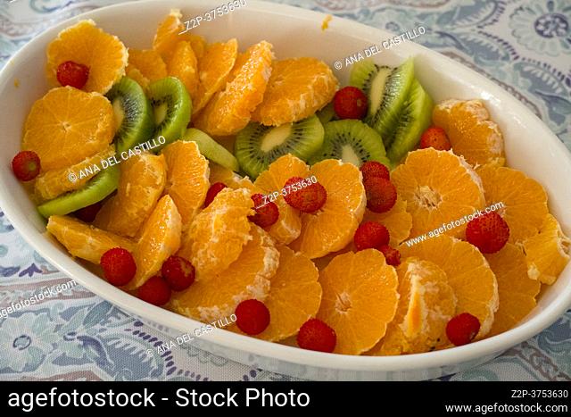 Oval platter with orange slices, arbutus fruit and kiwi, healthy dessert