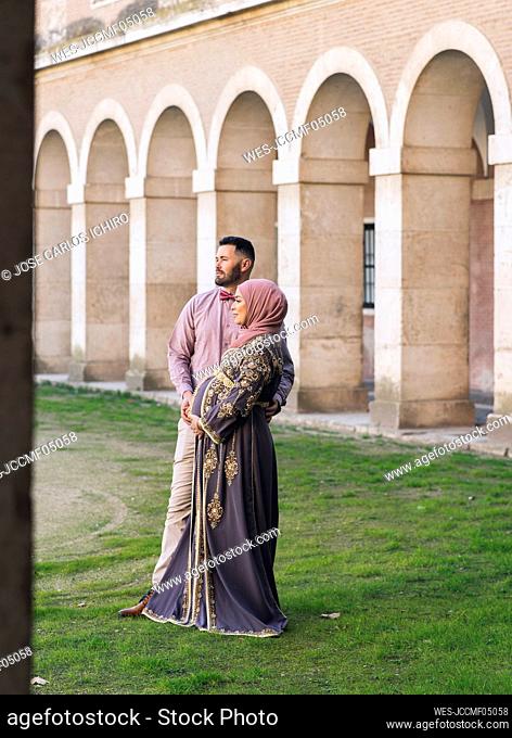 Husband with pregnant wife standing in park