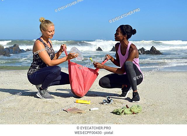 Two women cleaning the beach from plastic waste