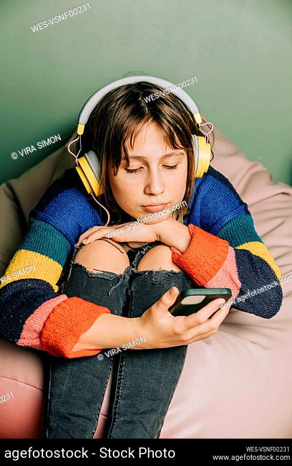 Girl wearing headphones using smart phone at home