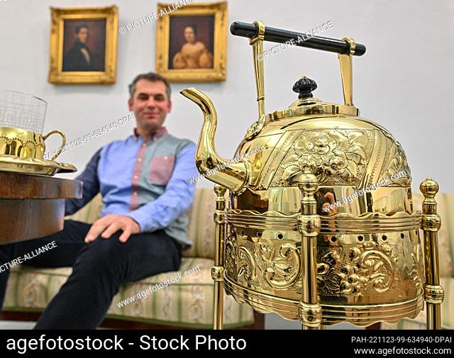 23 November 2022, Brandenburg, Frankfurt (Oder): Tim S. Müller, director of the Museum Viadrina, sits in the new exhibition ""Shiny things for tea...