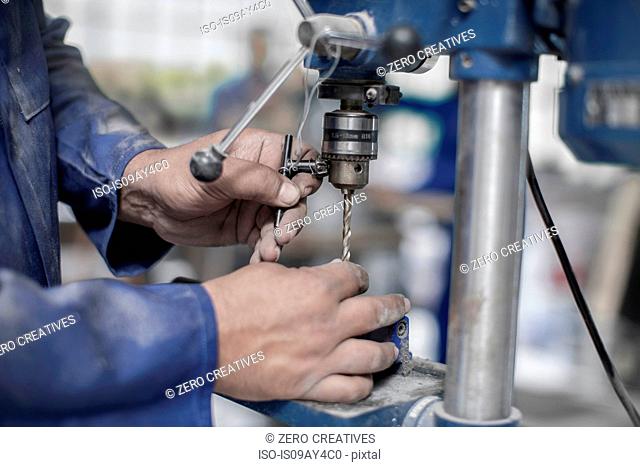 Close up of workers hands attaching drill bit in workshop