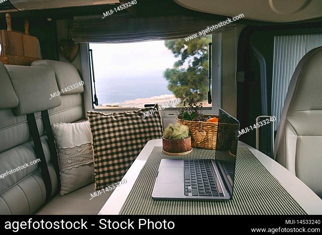 Travel lifestyle and online digital nomad workplace inside modern camper van. Laptop computer on the table and nature outside the window view