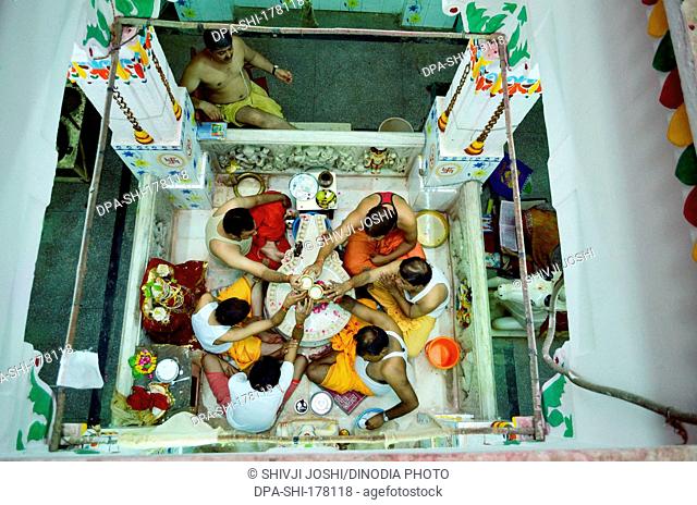 People performing Rudrabhishek around Shivling Pataleshwar temple Jodhpur Rajasthan India Asia
