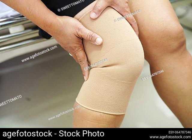 Asian senior woman wearing elastic support knee brace for reduce pain