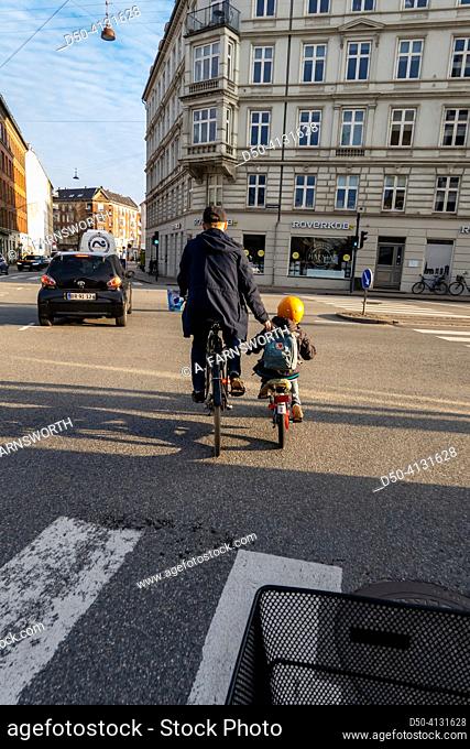 Copenhagen, Denmark A father guides his young son to ride a bicycle across a busy intersection on Vesterbrogade