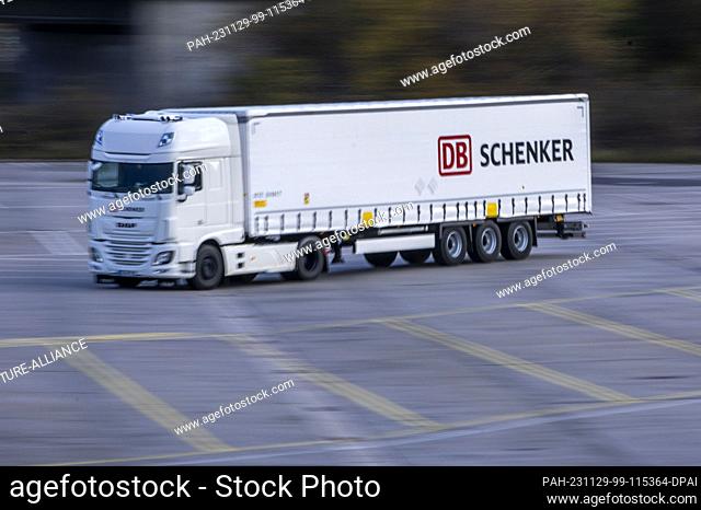 PRODUCTION - 21 November 2023, Mecklenburg-Western Pomerania, Rostock: A truck from the logistics company DB Schenker drives across the site of the logistics...