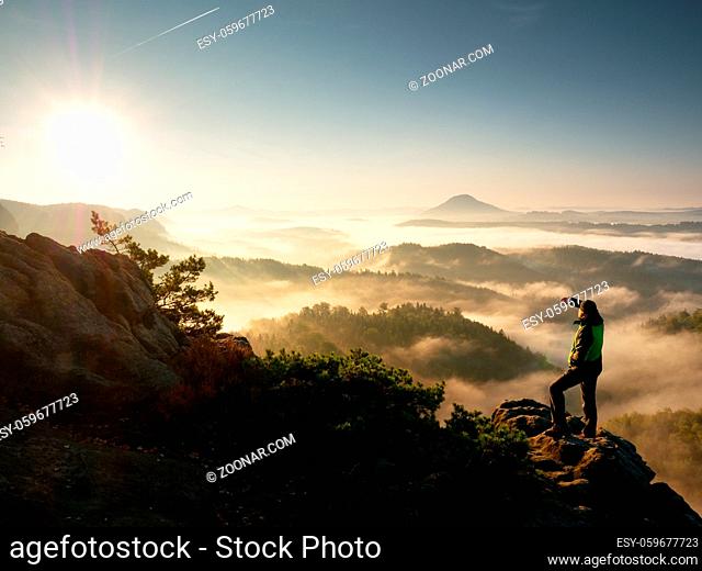 Man silhouette stay on sharp rock peak. Satisfy hiker enjoy view. Tall man on rocky cliff watching down to landscape. Vivid and strong vignetting effect
