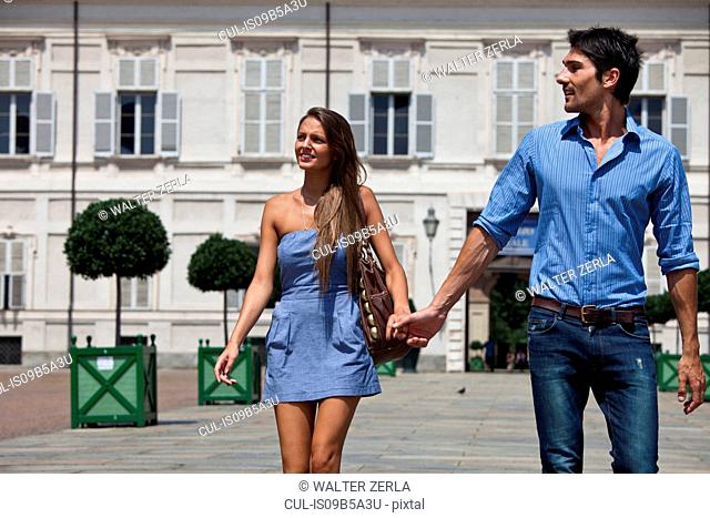Young couple walking outdoors, hand in hand, Turin, Piedmont, Italy