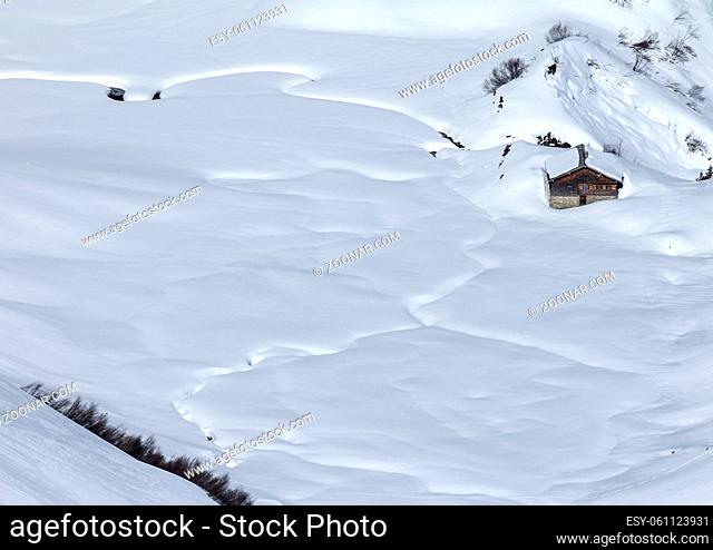 Romantic hut covered by snow in the alps seen from above