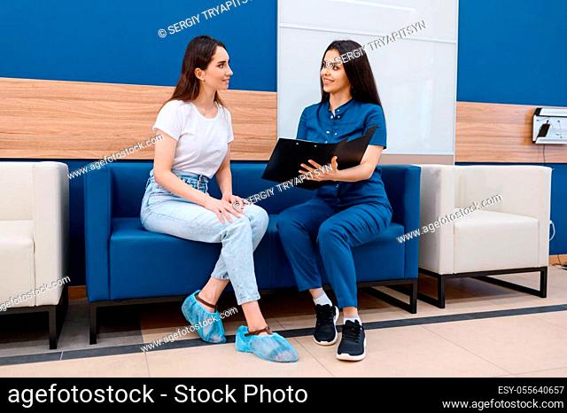 Female surgeon and patient sitting on sofa in clinic hall, surgery. Doctor in uniform, medical worker, medicine and health, professional healthcare in hospital