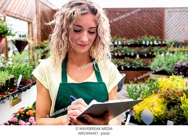 Female florist writing on clipboard