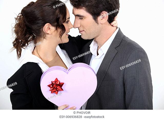 Couple holding heart-shaped box of chocolates