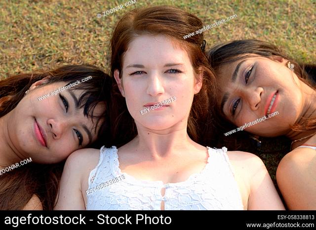 Portrait of three multi ethnic young beautiful women as friends together at the park outdoors