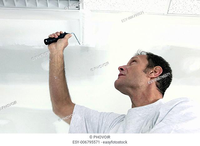 Painter using roller on ceiling