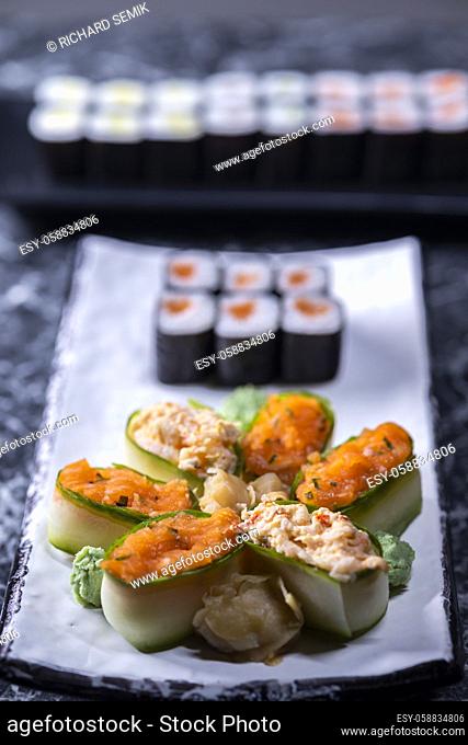 set of sushi rolls with seafood on a black stone background
