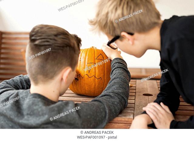 Two boys preparing a pumpkin for Halloween lantern