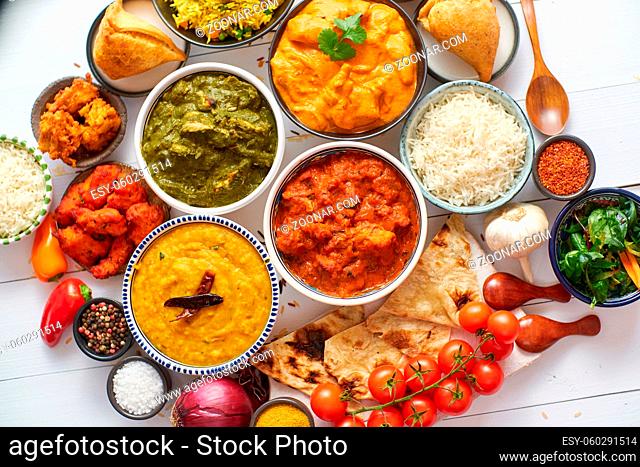 Assorted Indian various food with spices, rice and fresh vegetables on white wooden table. Flat lay. Top view