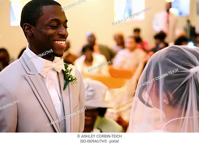 Bridegroom in church wedding ceremony smiling at bride