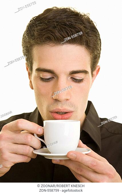 Junger Mann pustet vorsichtig in eine heiße Kaffeetasse