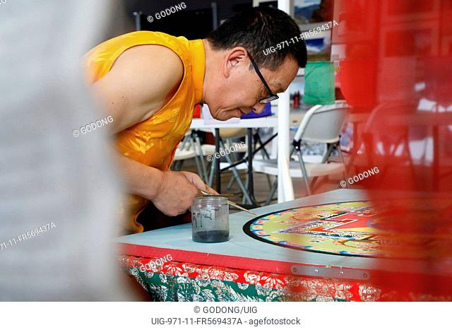 Tibetan Monk carefully works on a colorful Sand Mandala